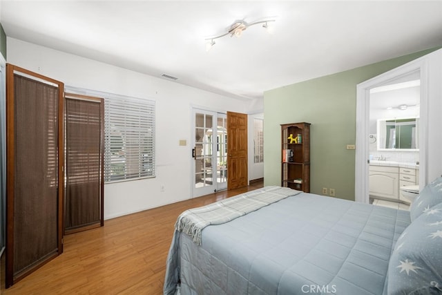 bedroom with visible vents, ensuite bathroom, and wood finished floors