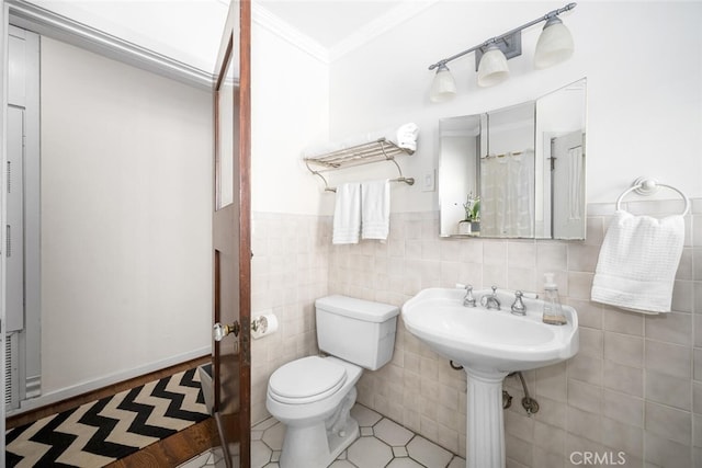 bathroom featuring crown molding, toilet, wainscoting, tile walls, and tile patterned floors