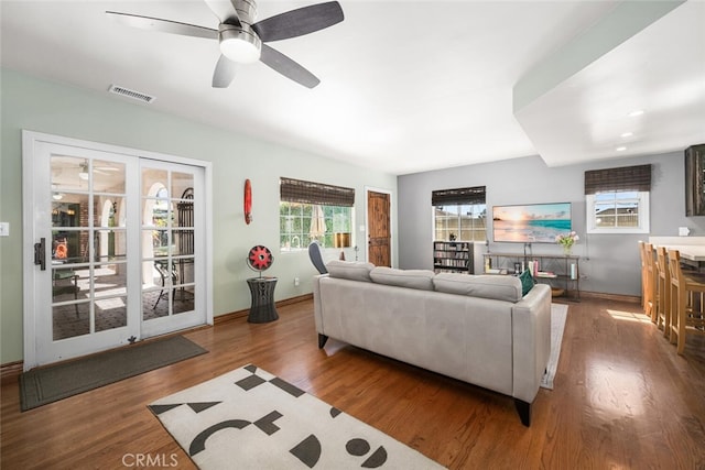 living room featuring visible vents, ceiling fan, wood finished floors, and baseboards