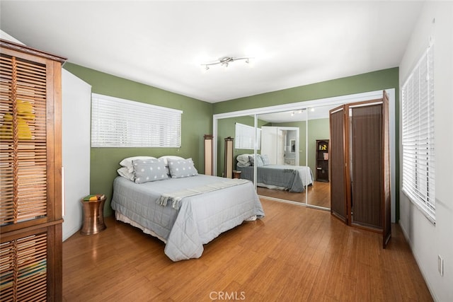 bedroom with rail lighting, a closet, and wood finished floors