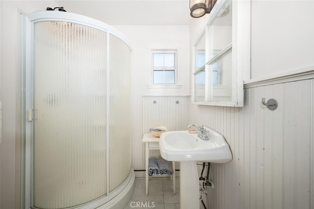 full bath featuring tile patterned flooring, a stall shower, wainscoting, and wood walls