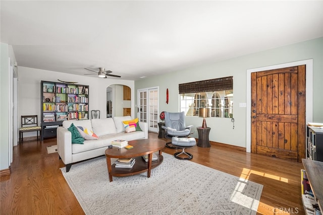 living room featuring french doors, arched walkways, wood finished floors, and a ceiling fan
