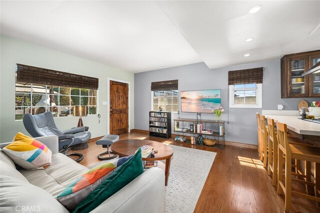 living area with a wealth of natural light, recessed lighting, wood finished floors, and baseboards