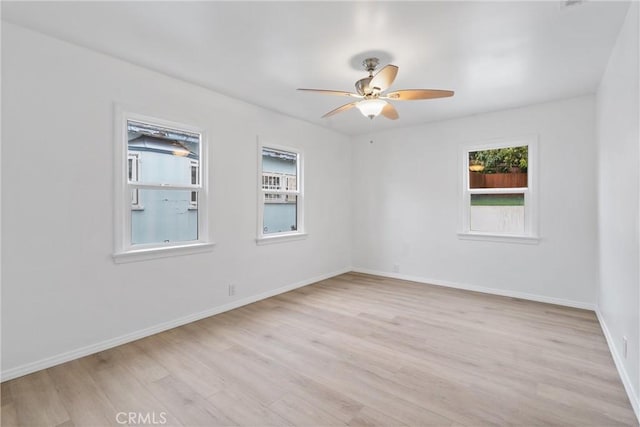 spare room with baseboards, light wood-type flooring, and a ceiling fan
