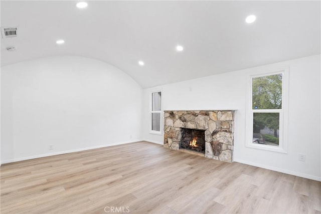 unfurnished living room with visible vents, a stone fireplace, light wood-style floors, recessed lighting, and lofted ceiling