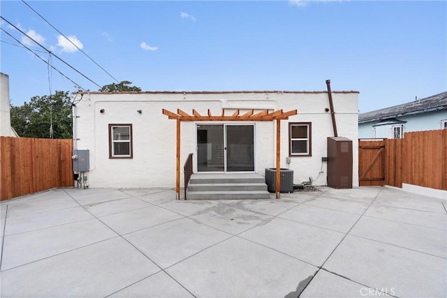 rear view of property featuring central air condition unit, a patio, stucco siding, and a gate