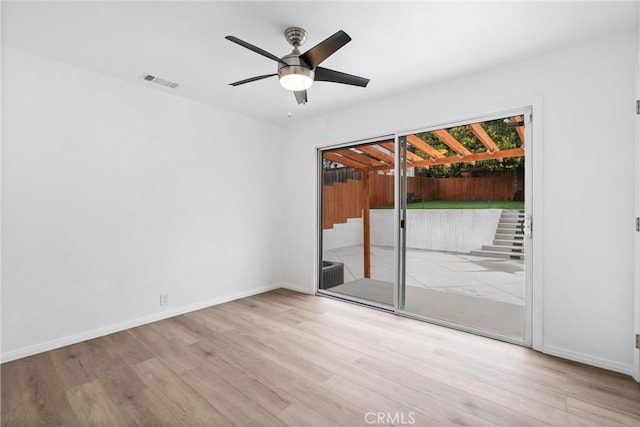 empty room featuring visible vents, ceiling fan, wood finished floors, and baseboards