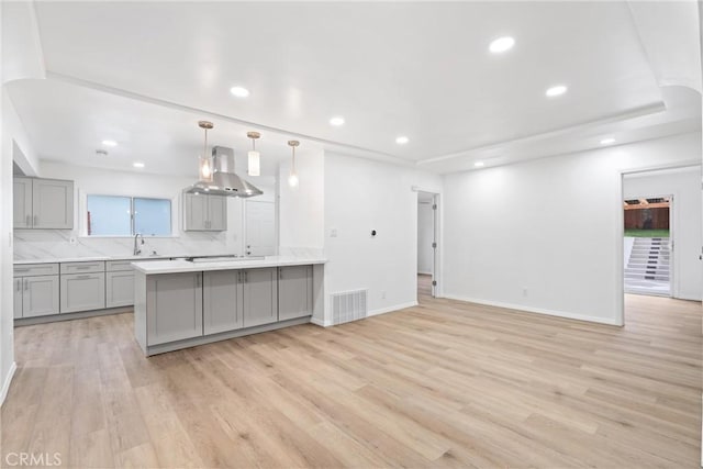 6010 S Verdun Ave, Los Angeles, CA 90043 - kitchen with gray cabinets, wall chimney exhaust hood, a sink, light wood-style floors, and light countertops
