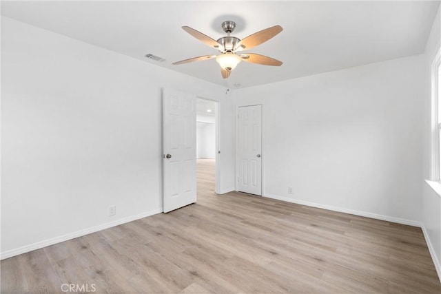 empty room featuring visible vents, baseboards, a ceiling fan, and wood finished floors