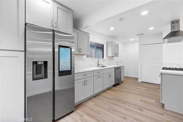 6010 S Verdun Ave, Los Angeles, CA 90043 - kitchen with wall chimney range hood, appliances with stainless steel finishes, a sink, gray cabinetry, and light wood finished floors
