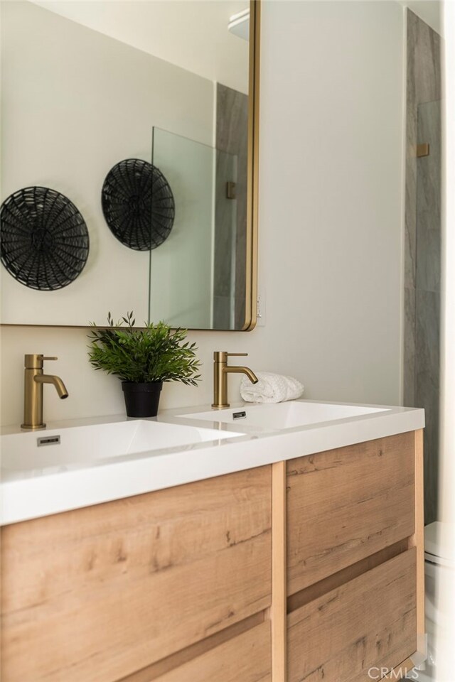 full bath featuring double vanity, toilet, a sink, and a shower