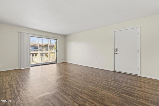 spare room with baseboards and wood finished floors