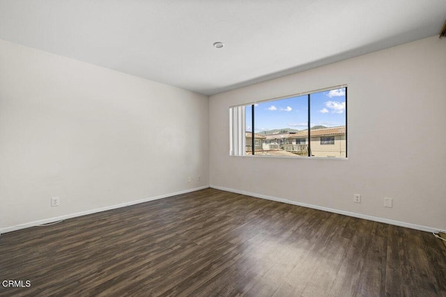 spare room featuring baseboards and wood finished floors