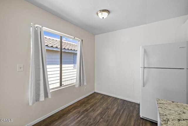 unfurnished dining area featuring dark wood-style floors and baseboards