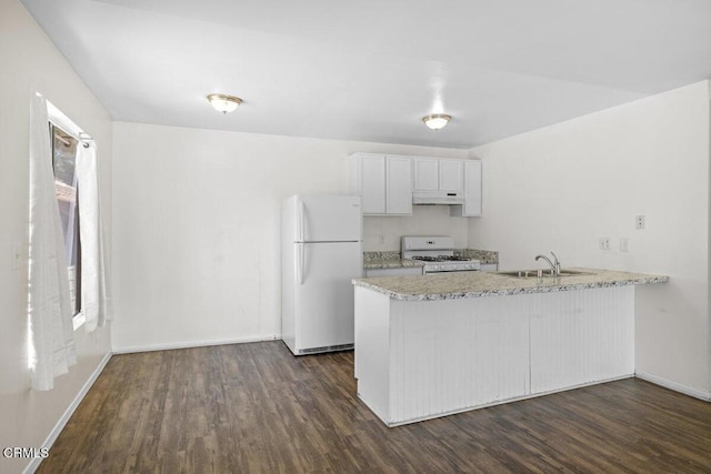 kitchen featuring a sink, a peninsula, under cabinet range hood, white appliances, and dark wood-type flooring