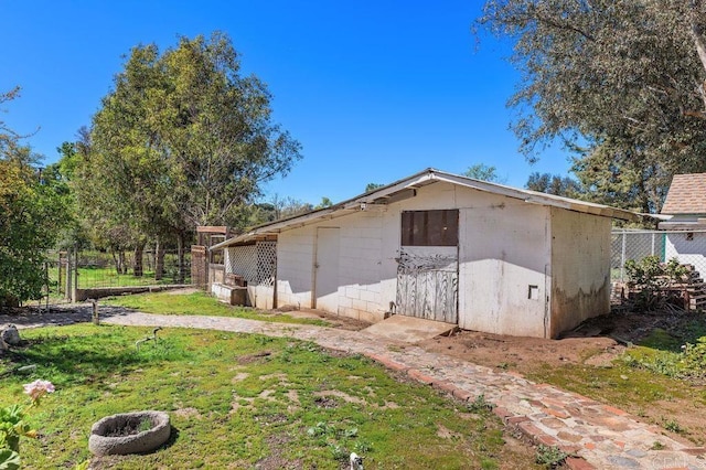 view of property exterior with an outbuilding, fence, and a lawn