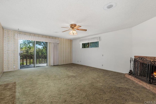unfurnished living room with ceiling fan, carpet, a brick fireplace, and wallpapered walls