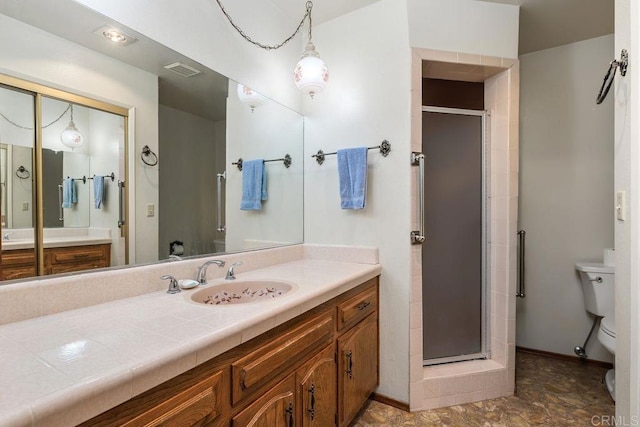 bathroom featuring a shower stall, vanity, baseboards, and toilet