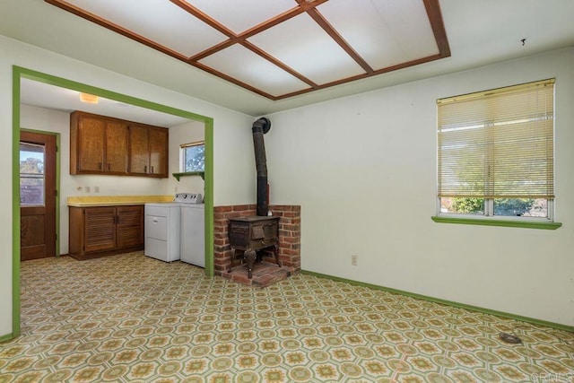 unfurnished living room featuring a wood stove, separate washer and dryer, and baseboards