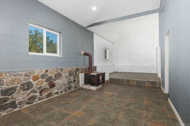 interior space with stone finish floor, a wood stove, and lofted ceiling