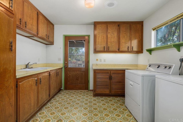 laundry area featuring independent washer and dryer, a sink, cabinet space, and a wealth of natural light