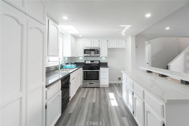 4706 W 168th St, Lawndale, CA 90260 - kitchen featuring stainless steel appliances, white cabinetry, light wood-style flooring, recessed lighting, and light stone counters