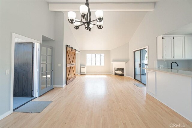 4706 W 168th St, Lawndale, CA 90260 - unfurnished living room with high vaulted ceiling, a barn door, a chandelier, beam ceiling, and light wood-type flooring