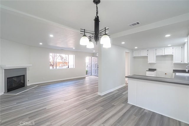 4706 W 168th St, Lawndale, CA 90260 - kitchen featuring recessed lighting, white cabinetry, light wood finished floors, a glass covered fireplace, and pendant lighting