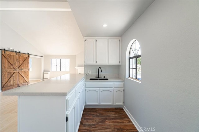 4706 W 168th St, Lawndale, CA 90260 - kitchen with a peninsula, dark wood finished floors, white cabinetry, light countertops, and a barn door