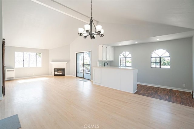 4706 W 168th St, Lawndale, CA 90260 - unfurnished living room featuring a chandelier, wood finished floors, high vaulted ceiling, recessed lighting, and a glass covered fireplace
