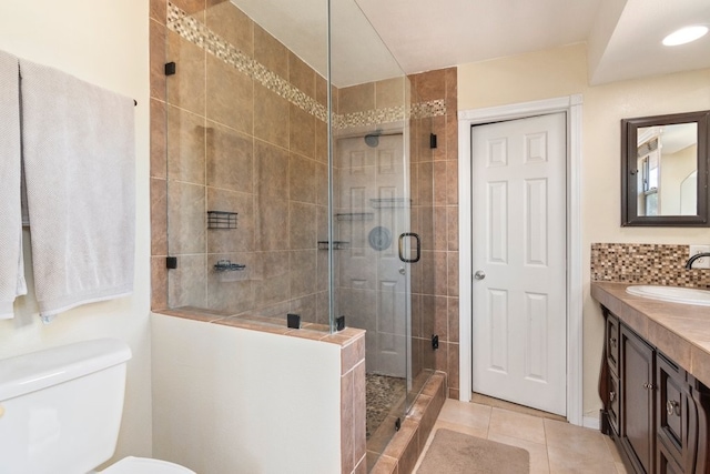 bathroom with a shower stall, vanity, tile patterned flooring, and toilet