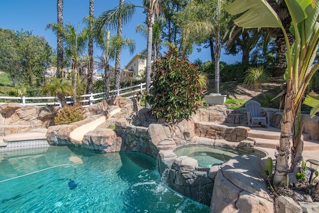 outdoor pool with fence and an in ground hot tub