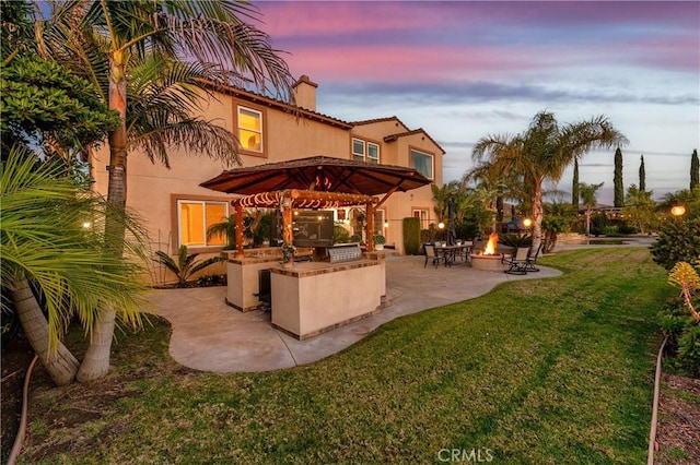 16720 S Peak Ct, Riverside, CA 92503 - back of house at dusk featuring a fire pit, a chimney, area for grilling, and stucco siding