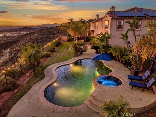16720 S Peak Ct, Riverside, CA 92503 - pool at dusk featuring a patio area, a fenced backyard, a pool with connected hot tub, and a mountain view