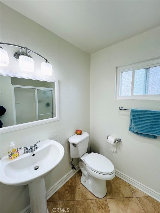bathroom featuring baseboards, tile patterned floors, a stall shower, and toilet