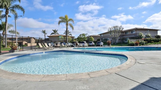 community pool with fence, a residential view, and a patio area