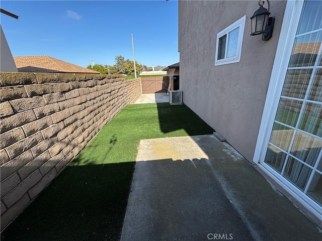 view of yard featuring central AC unit, a fenced backyard, and a patio area