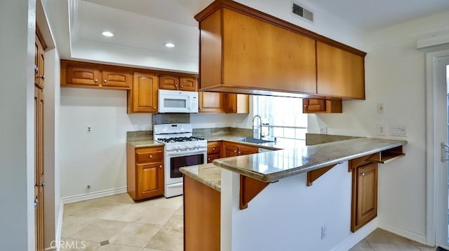 kitchen with brown cabinets, a sink, white appliances, recessed lighting, and a peninsula