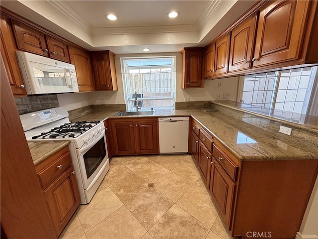 kitchen featuring a sink, crown molding, a tray ceiling, and white appliances