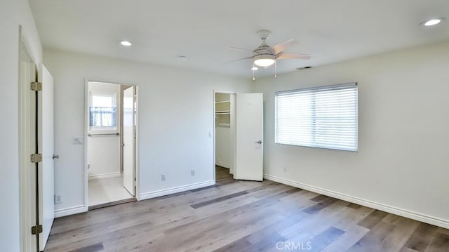 unfurnished bedroom featuring baseboards, multiple windows, wood finished floors, and visible vents
