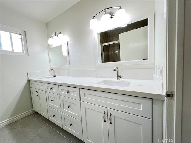 bathroom with double vanity, baseboards, a shower stall, and a sink