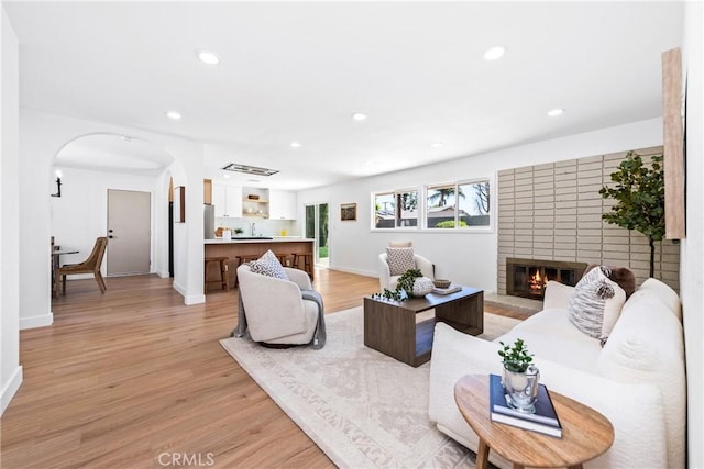 living area featuring recessed lighting, light wood finished floors, baseboards, and arched walkways