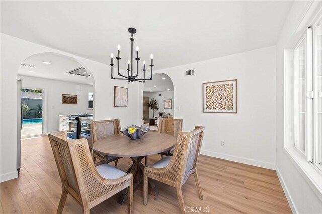 dining space featuring visible vents, arched walkways, and light wood finished floors
