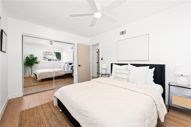 bedroom featuring wood finished floors, visible vents, radiator heating unit, and a closet