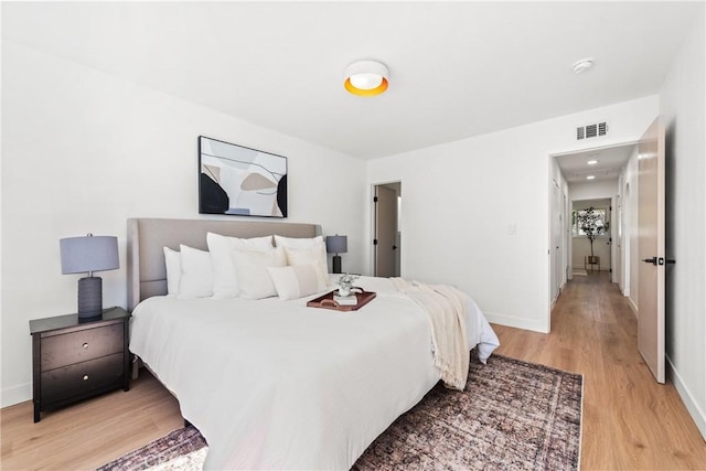 bedroom featuring light wood finished floors, visible vents, and baseboards