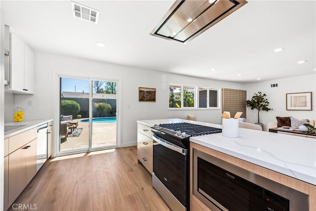 kitchen featuring a healthy amount of sunlight, visible vents, stainless steel gas range, and light wood-type flooring