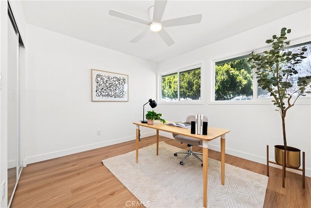 office area featuring baseboards, ceiling fan, and light wood-style floors