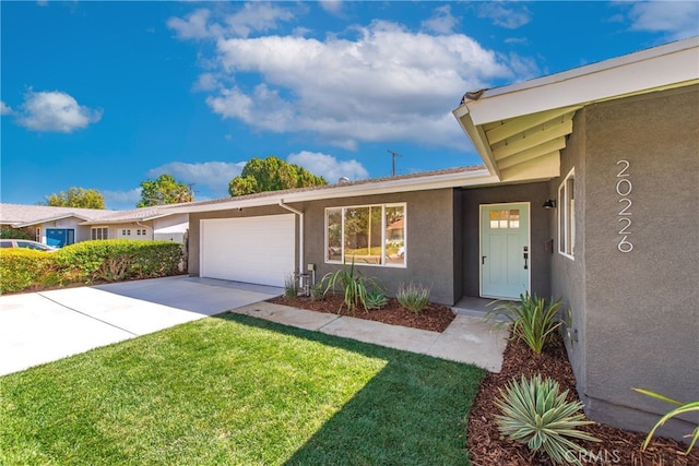 view of front facade with stucco siding, a front lawn, concrete driveway, and an attached garage
