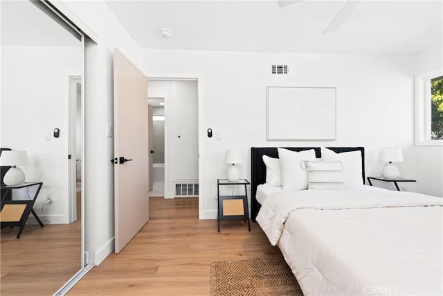 bedroom with visible vents, light wood finished floors, and baseboards
