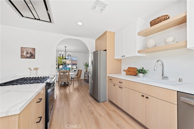 kitchen featuring arched walkways, light brown cabinetry, stainless steel appliances, a sink, and visible vents